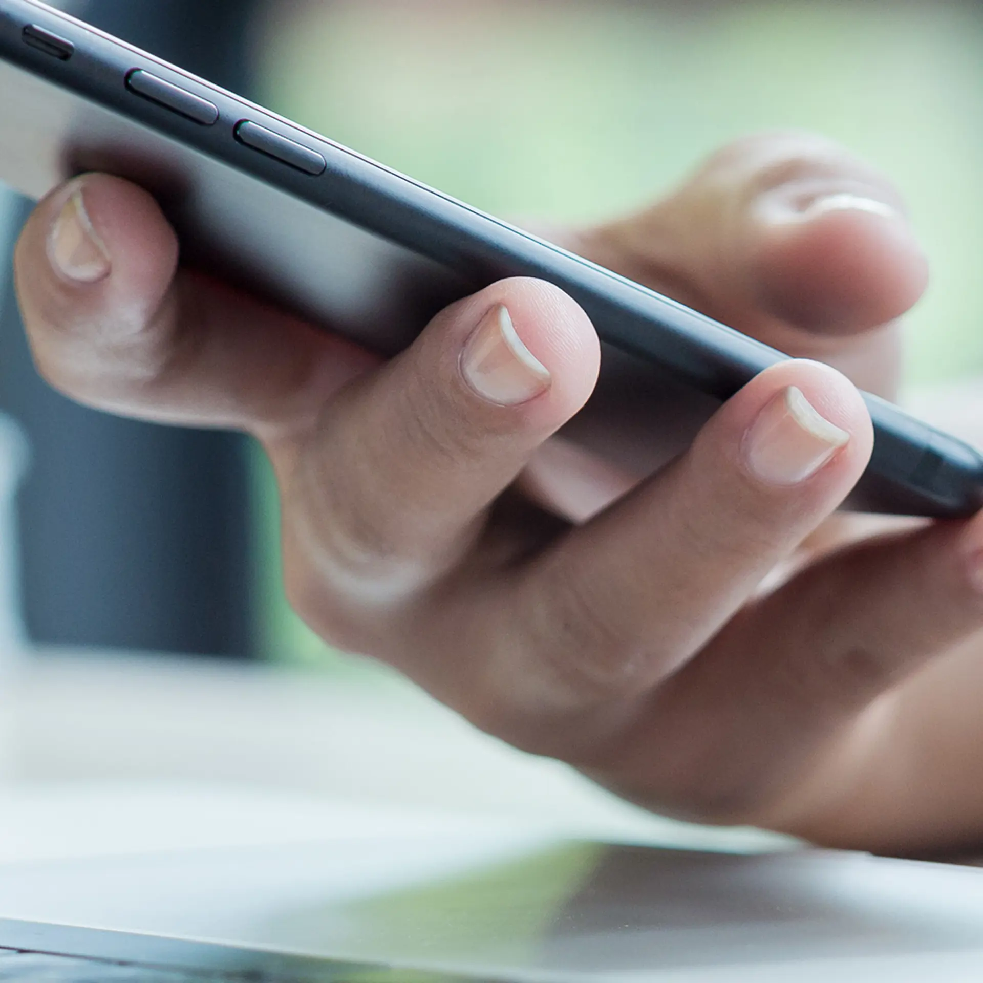 Kvinde holder telefon i hånden mens hun logger ind på sin computer