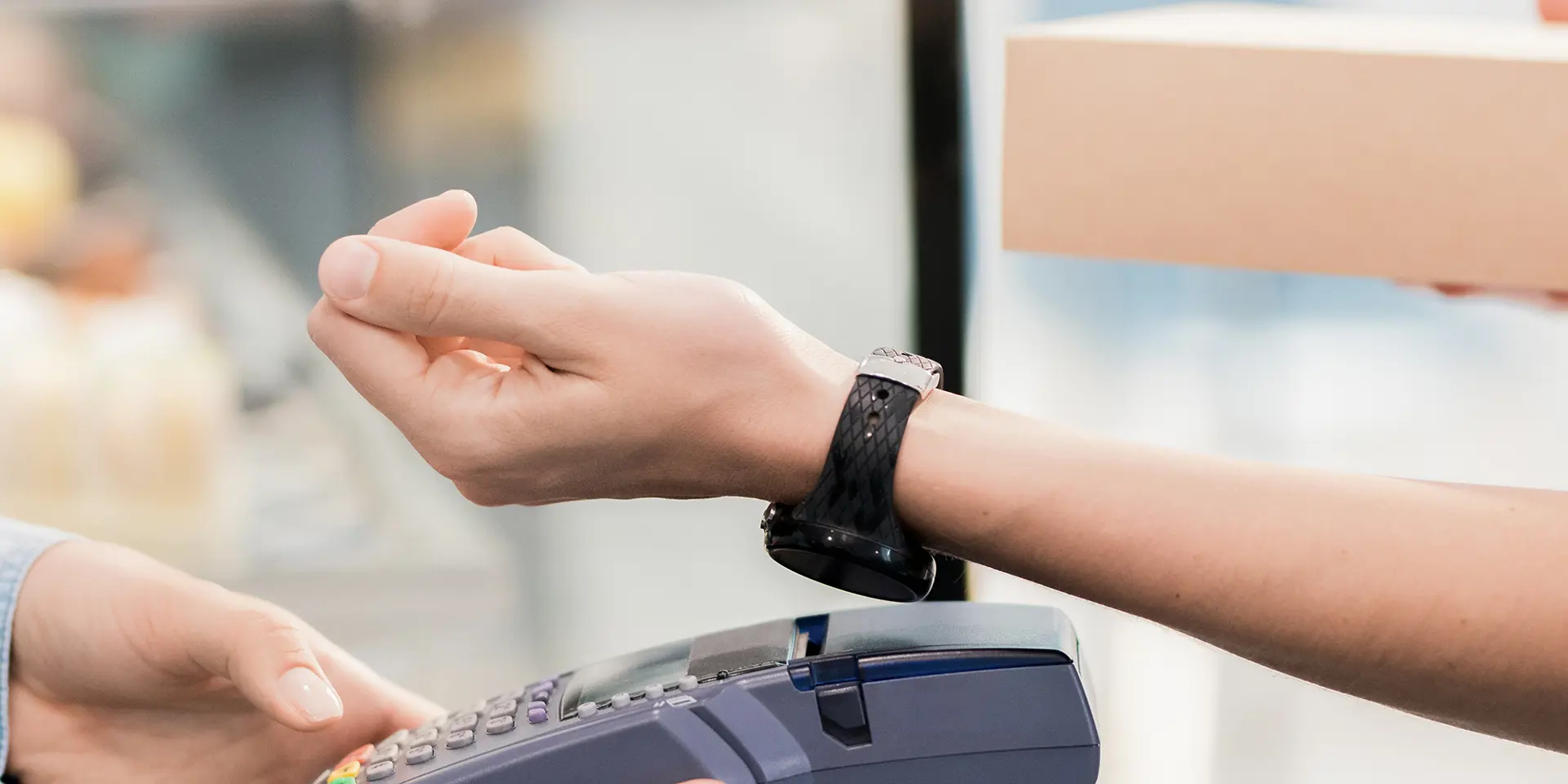 Personer bruger sit smartwatch til at betale ved en kasseekspedient med Fitpay, 