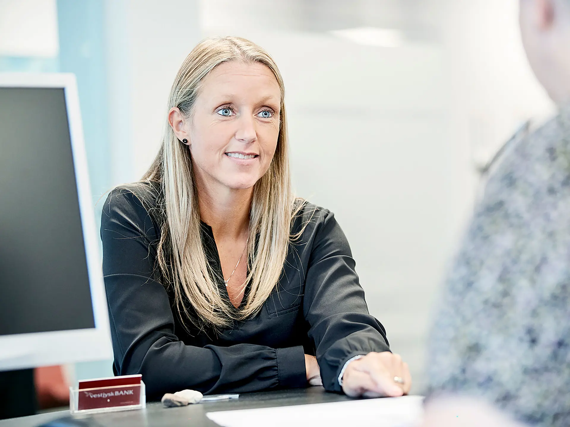 I Vestjysk Bank sidder rådgiver med lyst hår og snakker med ny kunde
