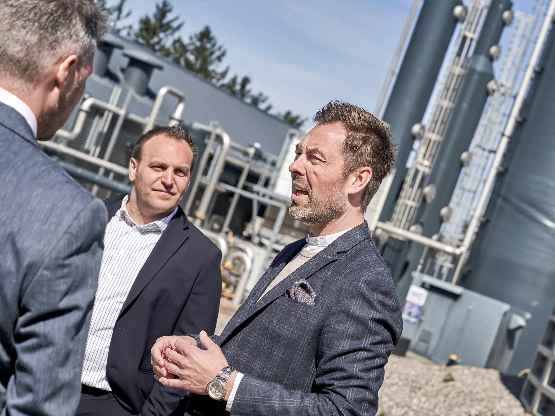 3 bankrådgivere i jakkesæt snakker om fordele ved Biogas som vedvarende energikilde