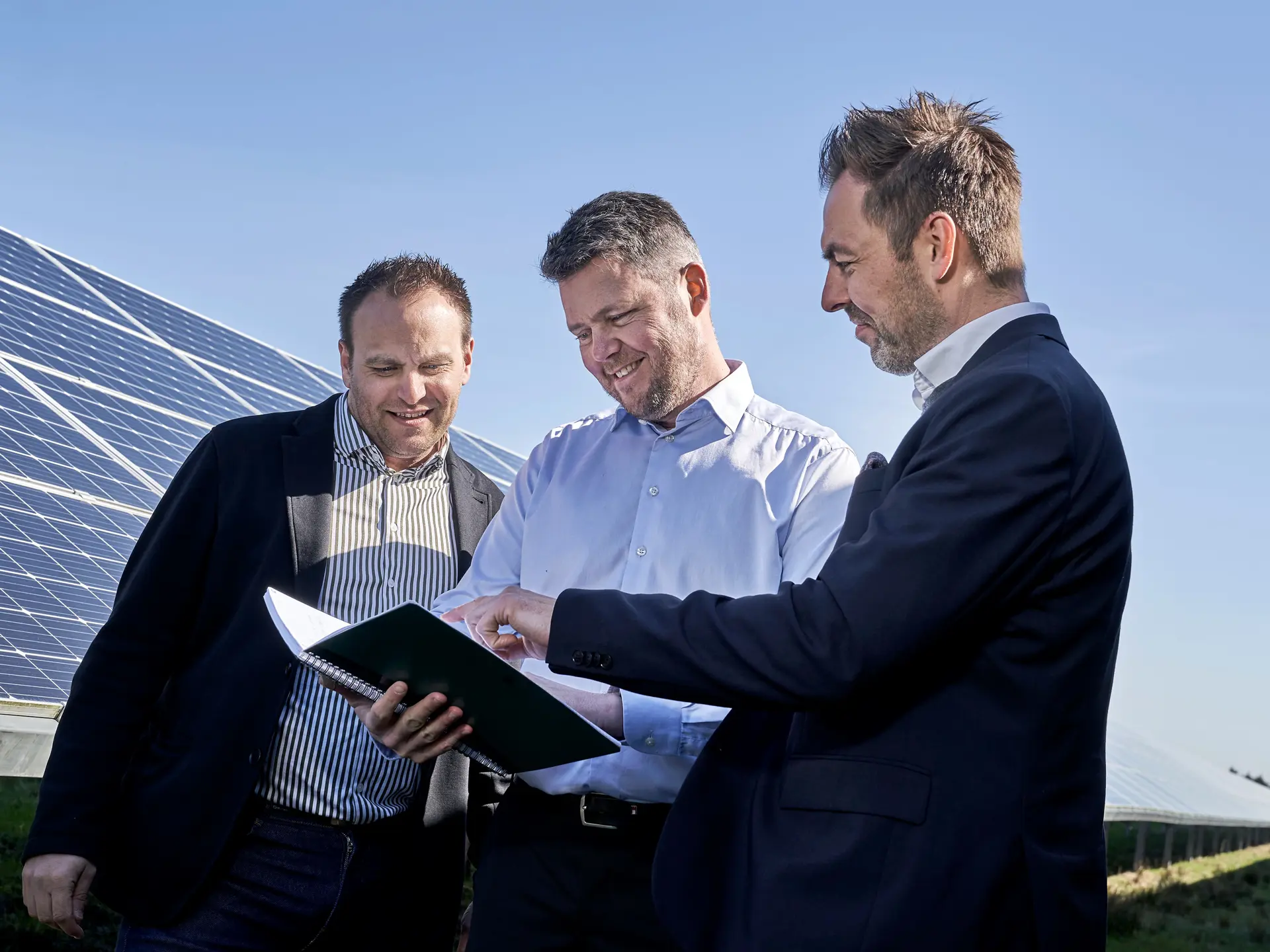 3 rådgivere gennemgår papir foran solceller