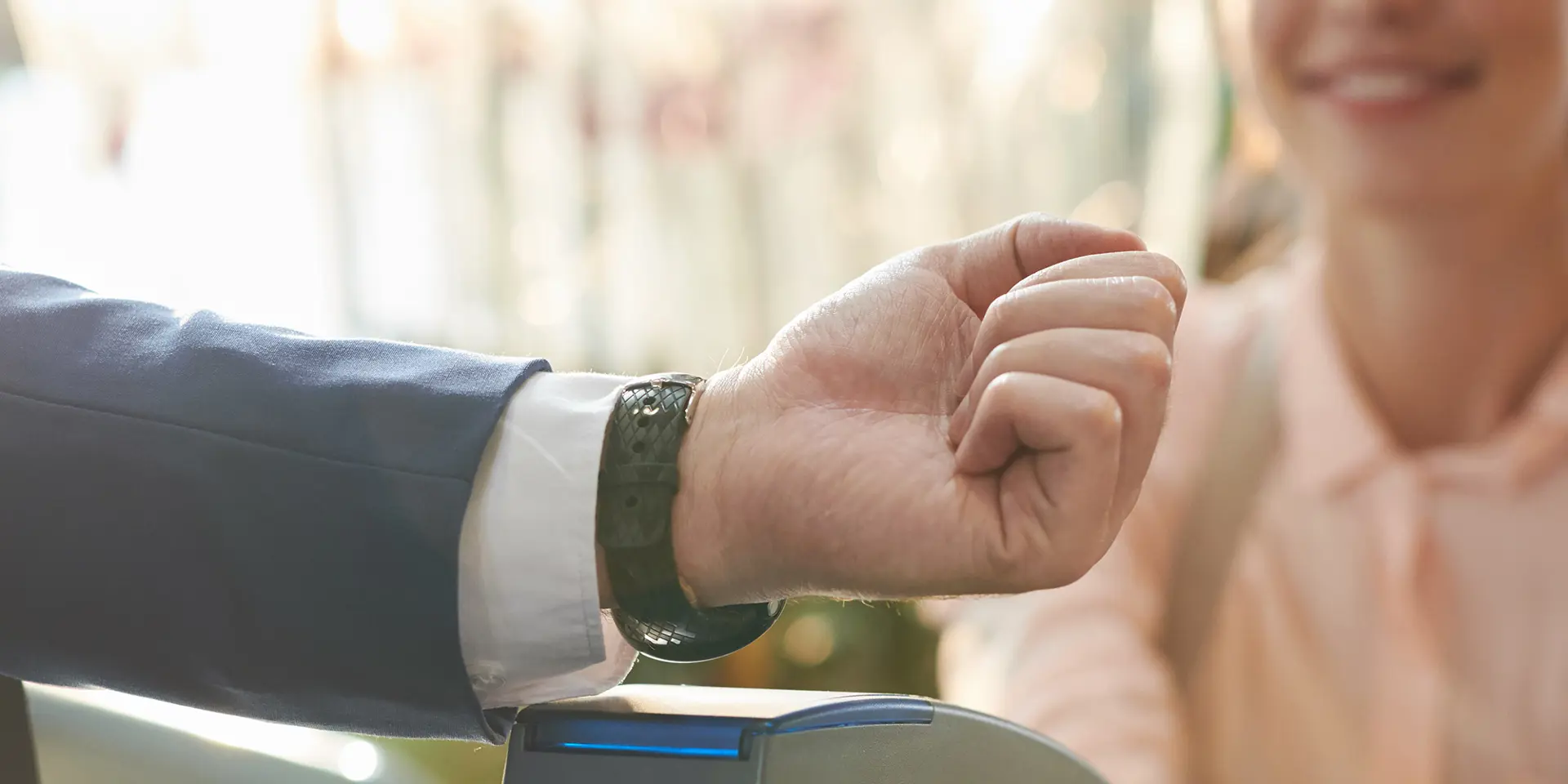 Mand i jakkesæt bruger sit smartwatch til at betale ved en kasseekspedient