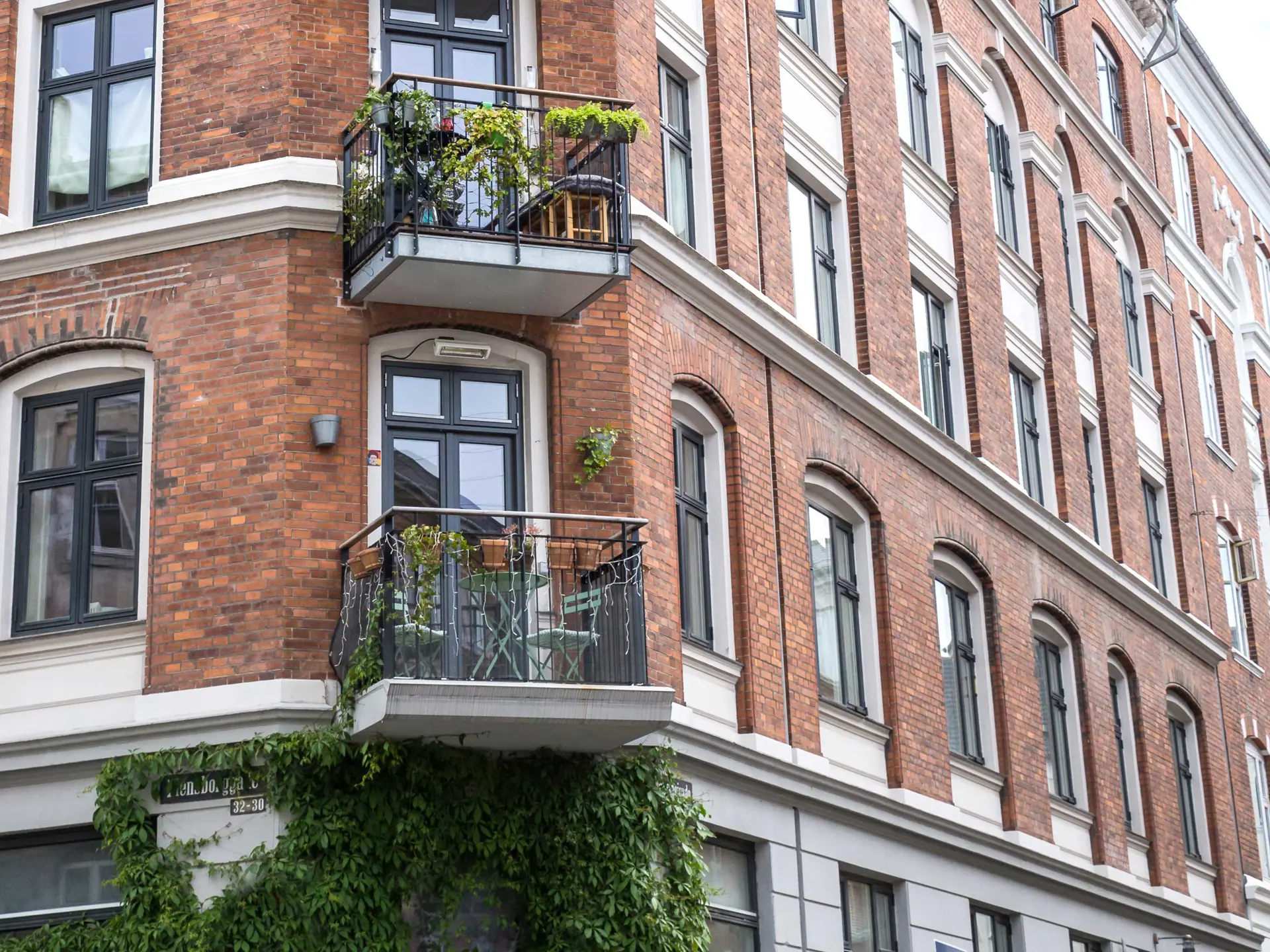 Lejlighedskompleks i rød farve i 4 etager med små terrasser og voksende planter på væggene