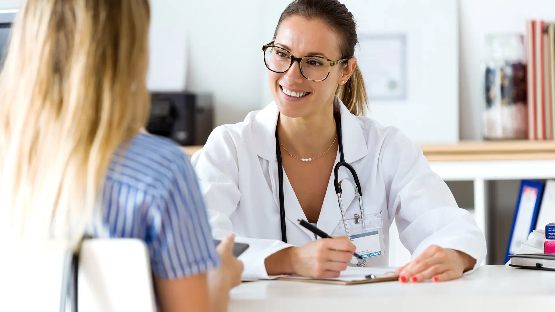 Kvindelige læge med briller snakker med patient